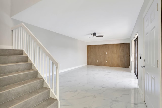 interior space featuring ceiling fan and wood walls