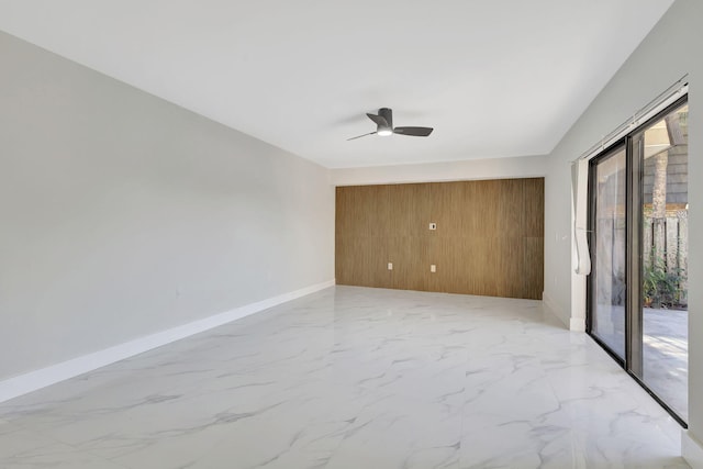 spare room featuring ceiling fan and wooden walls