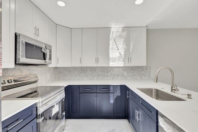 kitchen featuring appliances with stainless steel finishes, backsplash, sink, blue cabinetry, and white cabinets