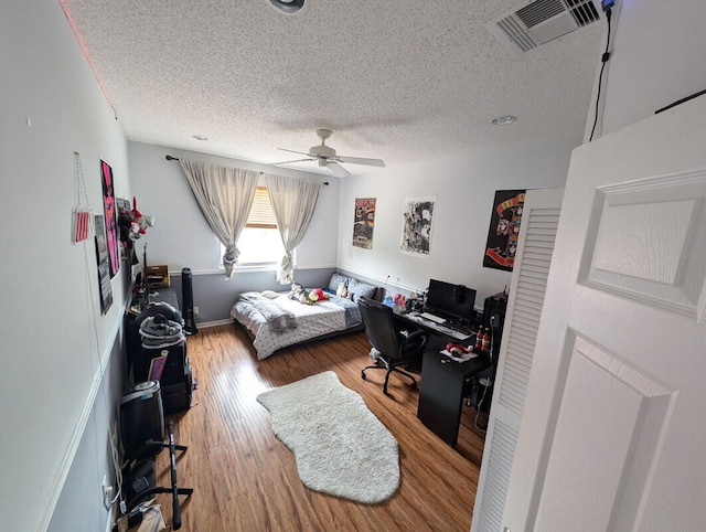 bedroom featuring hardwood / wood-style flooring, ceiling fan, and a textured ceiling