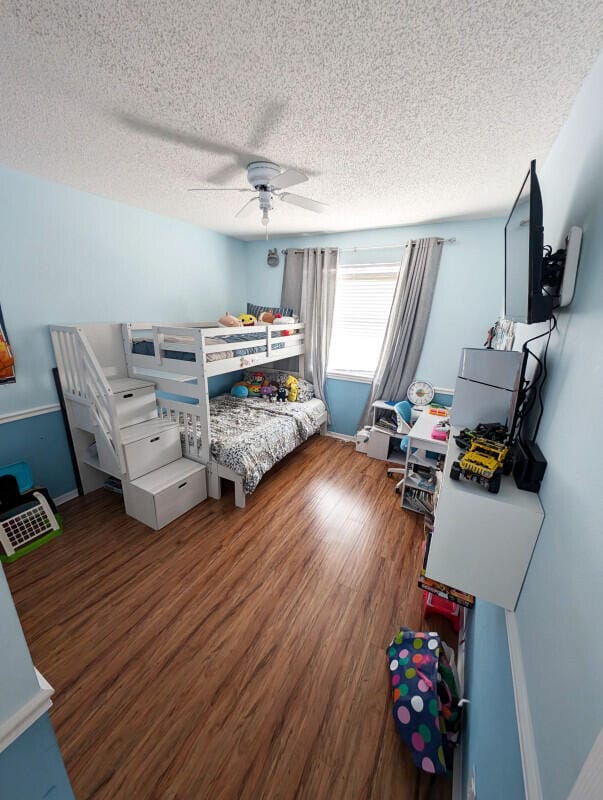 bedroom featuring ceiling fan, wood-type flooring, and a textured ceiling