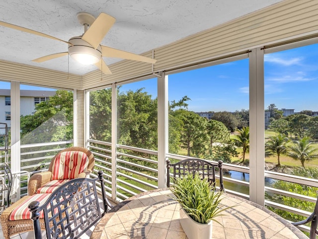 sunroom / solarium with a water view, plenty of natural light, and ceiling fan