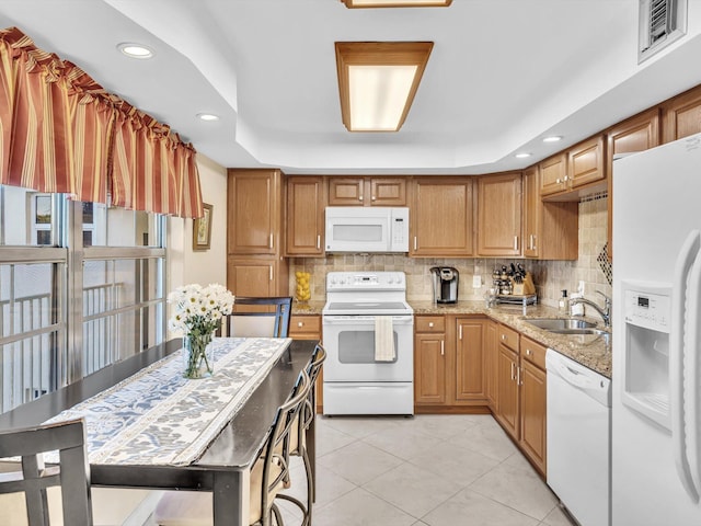 kitchen with white appliances, a raised ceiling, sink, light stone countertops, and tasteful backsplash