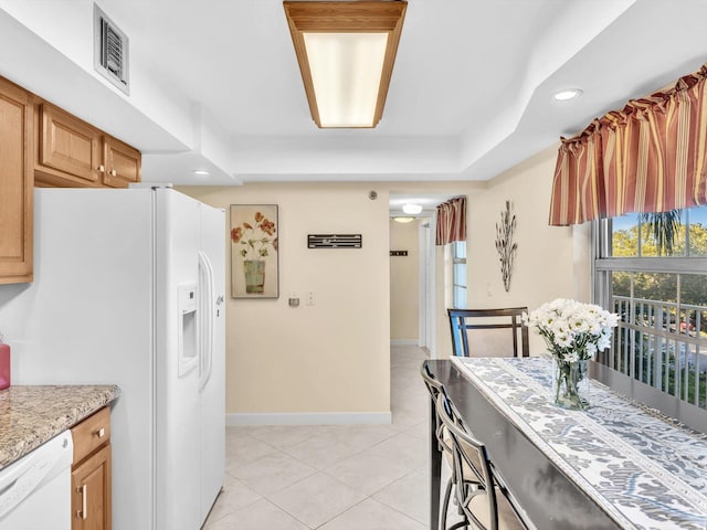 kitchen featuring a raised ceiling, light tile patterned flooring, and white appliances