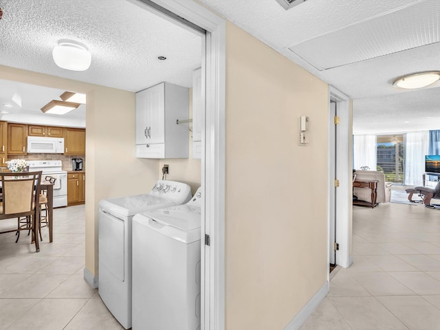 laundry room featuring separate washer and dryer, light tile patterned floors, cabinets, and a textured ceiling