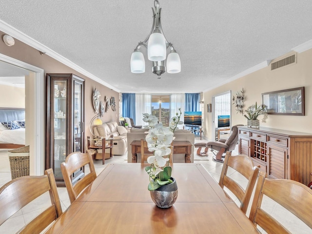 tiled dining area with ornamental molding, visible vents, a notable chandelier, and a textured ceiling