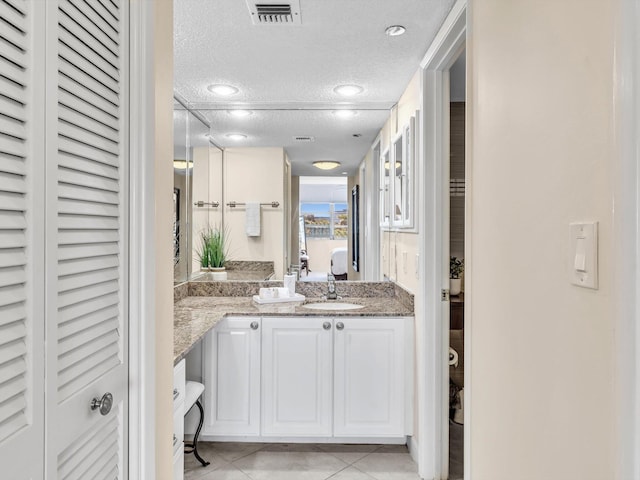 bathroom with vanity, a textured ceiling, and tile patterned floors