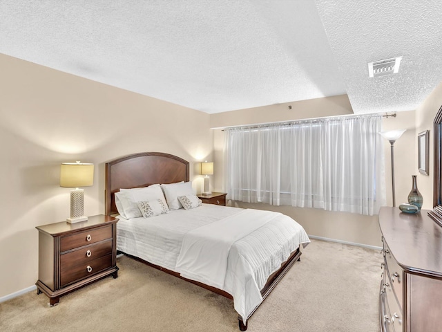 bedroom with a textured ceiling and light colored carpet