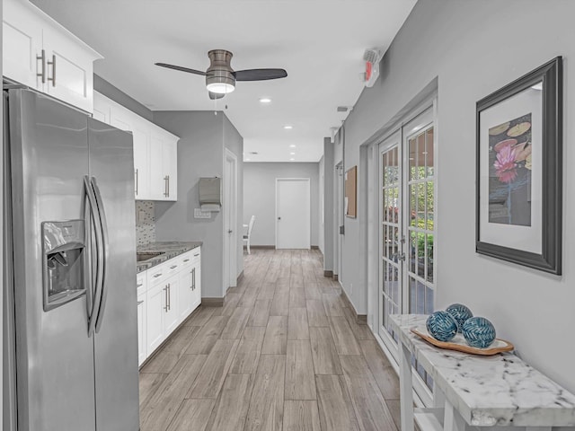 kitchen with white cabinetry, light wood-type flooring, stainless steel fridge with ice dispenser, and light stone counters