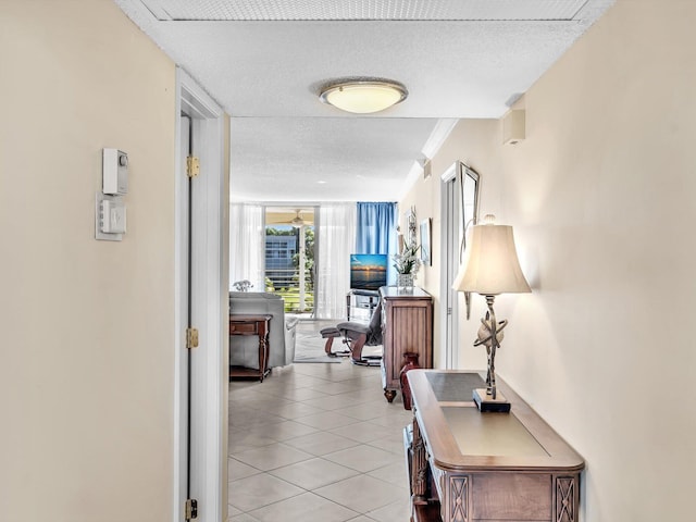 hall with light tile patterned floors, crown molding, a wall of windows, and a textured ceiling