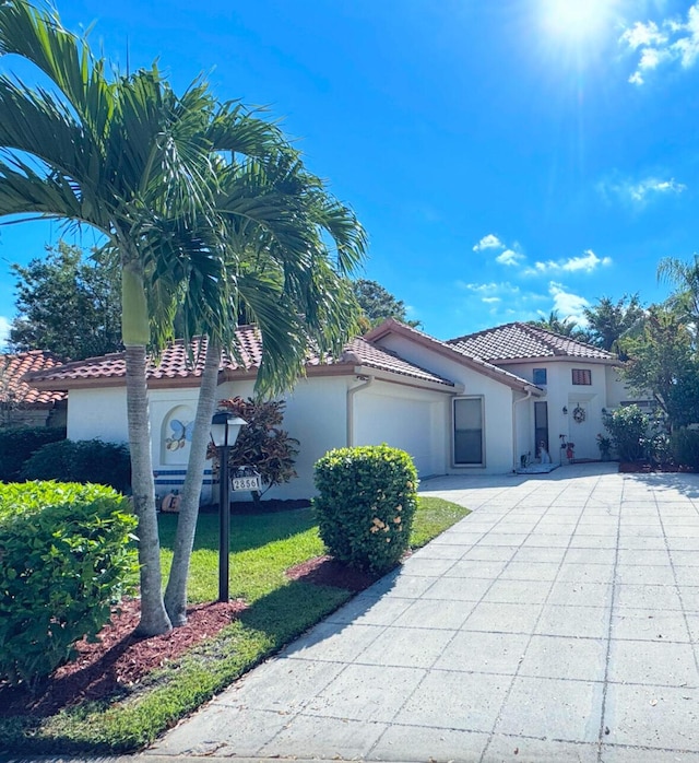 mediterranean / spanish house with a garage and a front lawn