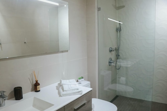 bathroom featuring a tile shower, vanity, tile walls, and toilet