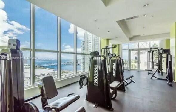 gym with floor to ceiling windows and a water view