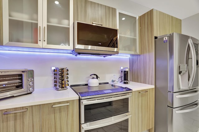 kitchen with tile patterned flooring, appliances with stainless steel finishes, and light brown cabinets