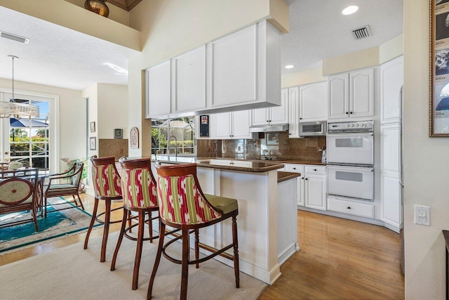 kitchen featuring double oven, kitchen peninsula, and white cabinets