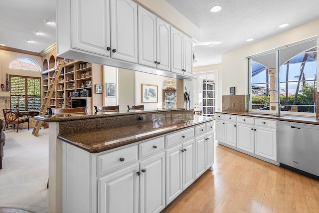 kitchen featuring stainless steel dishwasher, kitchen peninsula, sink, and white cabinets