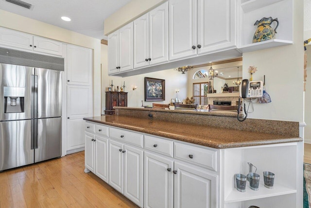 kitchen featuring stainless steel built in fridge, white cabinets, and light wood-type flooring