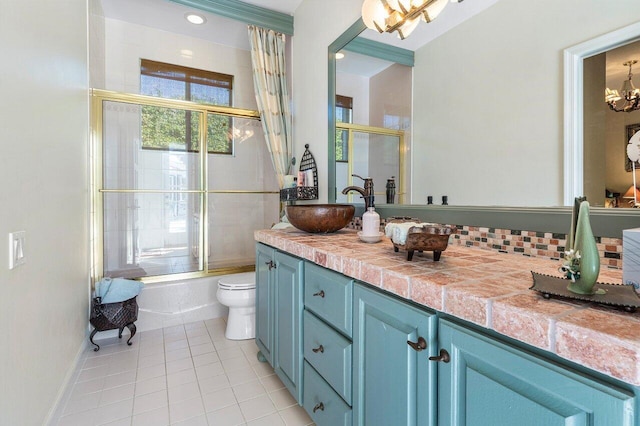 full bathroom with tile patterned floors, toilet, a chandelier, vanity, and enclosed tub / shower combo