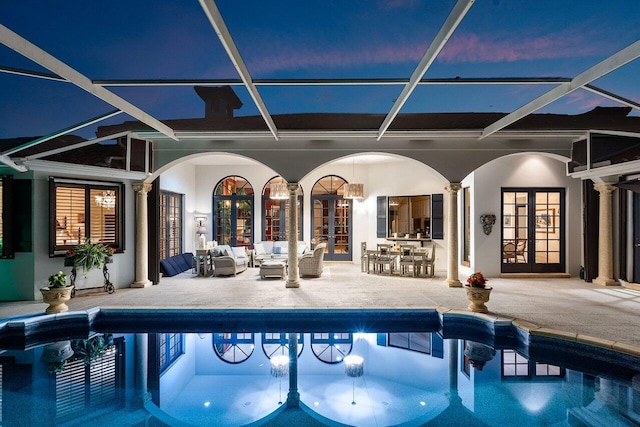 pool at dusk with a bar, a patio, a lanai, and french doors