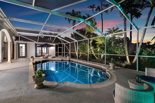 pool at dusk with french doors, a lanai, and a patio area