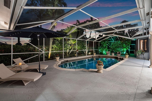 pool at dusk featuring a lanai and a patio