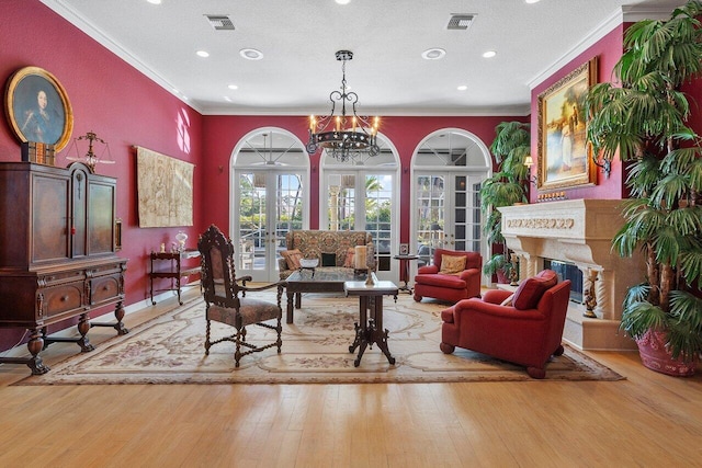 sitting room featuring ornamental molding, a textured ceiling, light hardwood / wood-style floors, and french doors