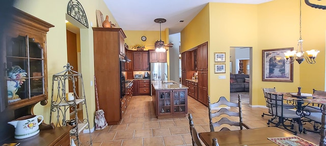 kitchen featuring light stone countertops, sink, decorative light fixtures, and stainless steel refrigerator with ice dispenser