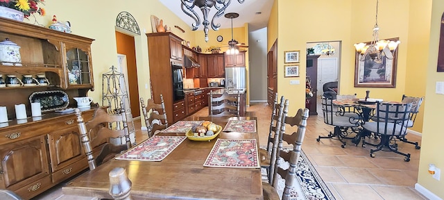 dining area featuring a high ceiling, a notable chandelier, and light tile patterned flooring