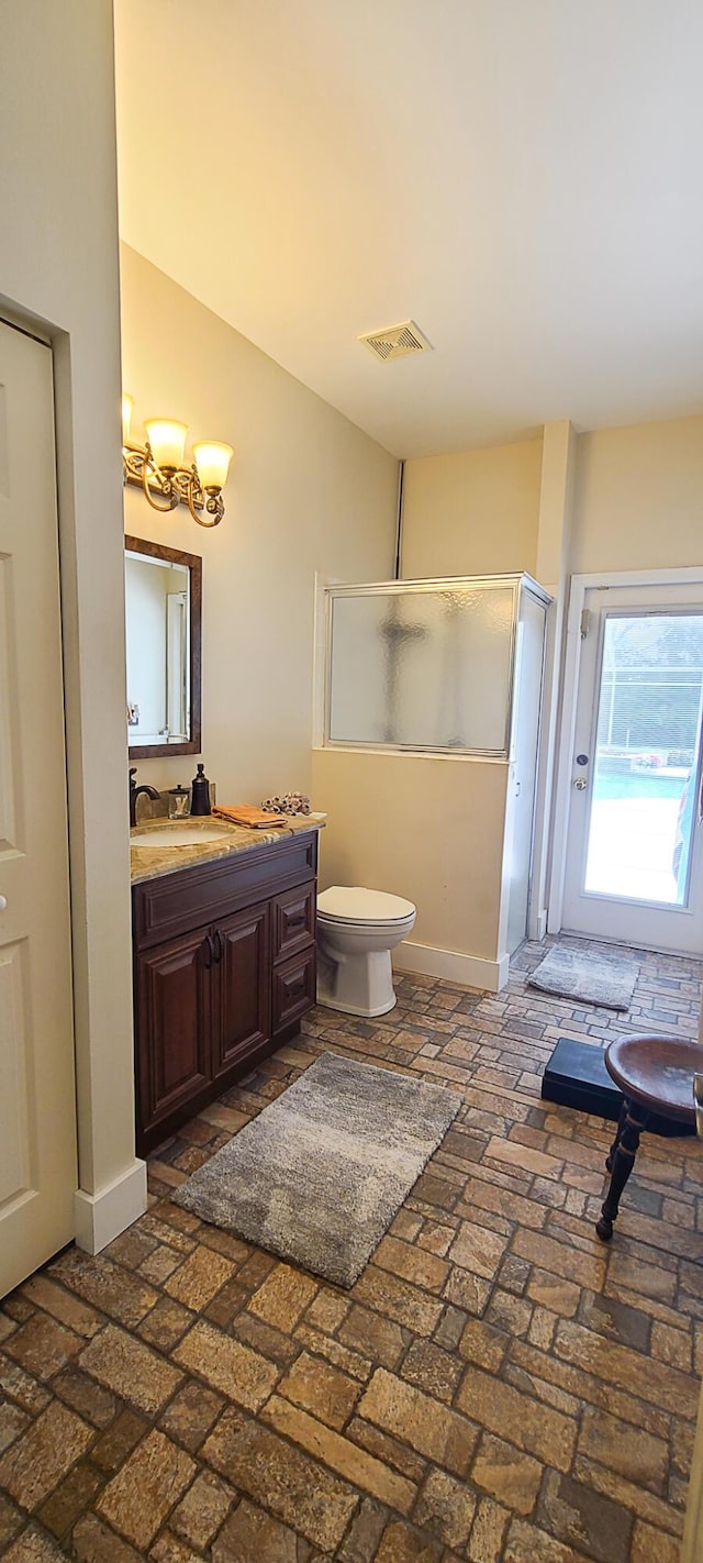 bathroom with vanity, toilet, and a shower with door