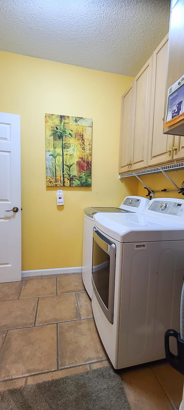 laundry area with cabinets, a textured ceiling, and washing machine and dryer