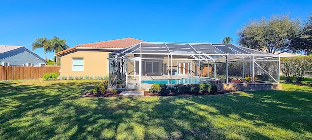 back of house featuring a lawn and glass enclosure