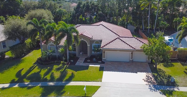 mediterranean / spanish-style home with a garage and a front lawn