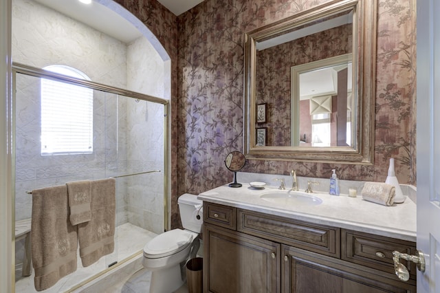 bathroom featuring vanity, toilet, and a shower with door