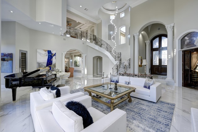 living room with french doors, a towering ceiling, decorative columns, and crown molding