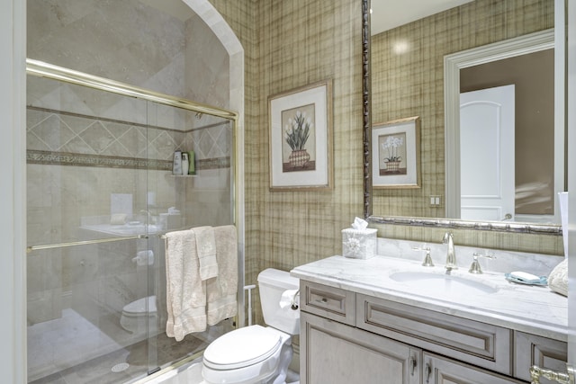 bathroom featuring vanity, a shower with shower door, and toilet