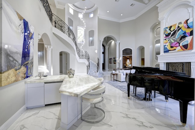 interior space with decorative columns, vanity, a high ceiling, and ornamental molding