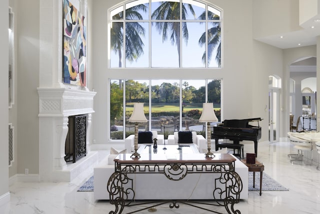 living room with a high end fireplace and a towering ceiling