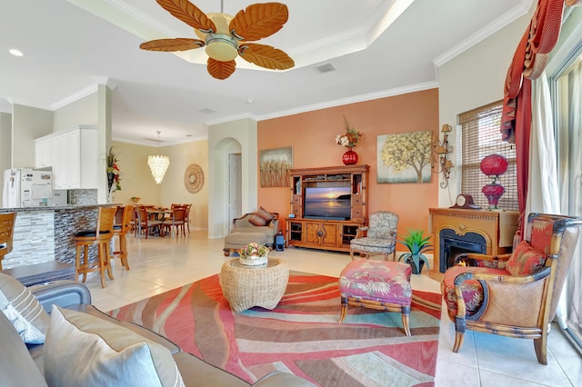 living room featuring light tile patterned floors, ceiling fan with notable chandelier, and ornamental molding