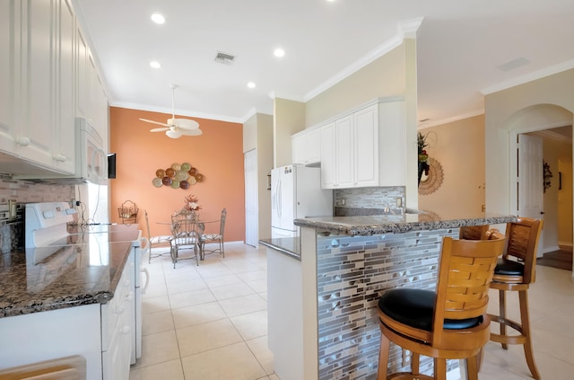 kitchen featuring tasteful backsplash, kitchen peninsula, crown molding, white appliances, and white cabinets