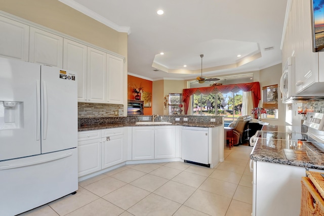 kitchen with white appliances, white cabinets, ceiling fan, a tray ceiling, and kitchen peninsula