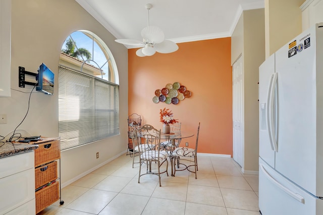 tiled dining room featuring a high ceiling, ceiling fan, and crown molding