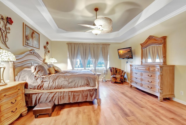 bedroom featuring ceiling fan, light hardwood / wood-style floors, a tray ceiling, and multiple windows