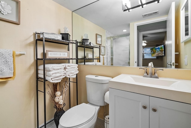 bathroom featuring toilet, ceiling fan, an enclosed shower, and vanity