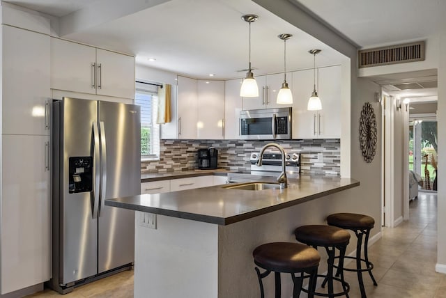 kitchen featuring white cabinetry, stainless steel appliances, and hanging light fixtures