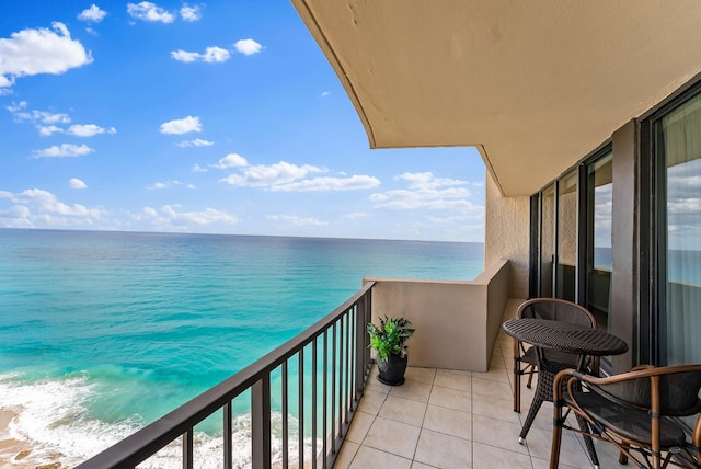 balcony with a water view and a view of the beach