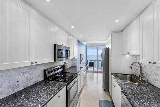 kitchen featuring sink, dark stone countertops, tasteful backsplash, white cabinetry, and stainless steel appliances