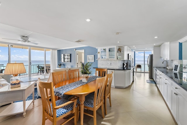 dining room featuring ceiling fan, a healthy amount of sunlight, a water view, and sink