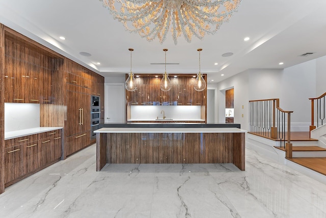 kitchen featuring a center island with sink, decorative light fixtures, and sink