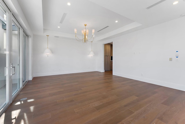 spare room with dark hardwood / wood-style flooring and a chandelier