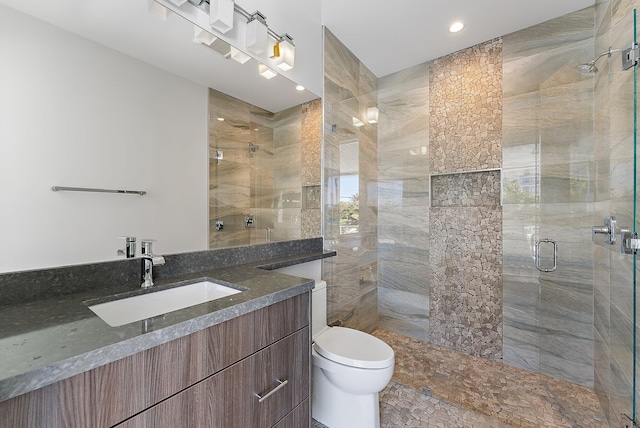 bathroom with vanity, toilet, and a shower with door